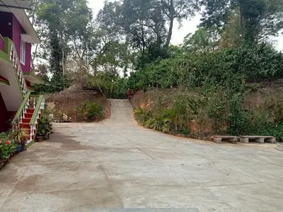 a dirt road next to a building with trees at Somanna Estate stay in Madikeri