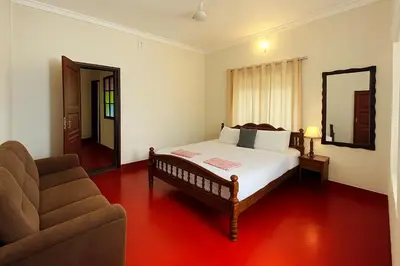 a bedroom with a bed and a couch and a mirror at Haris Farm House in Kannur