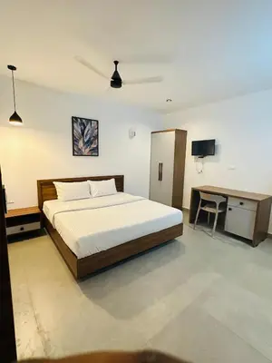 a bedroom with a bed and a desk in it at ZAHIR RESIDENCY calicut in Kozhikode