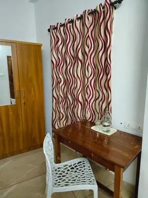 a room with a wooden table and a curtain at RF Tower Lodge in Kozhikode