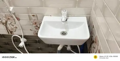 a white sink in a bathroom with white tiles at S M LODGe in Dharmapuri