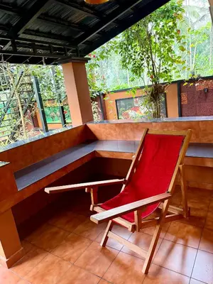 a red chair sitting in front of a window at Skylark Home in Mananthavady