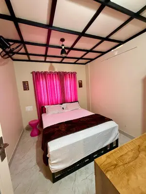 a bedroom with a large bed with a pink curtain at Skylark Home in Mananthavady