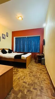 a bedroom with a bed and a window with blue curtains at KP Holidays తెలుగు Cottage in Ooty