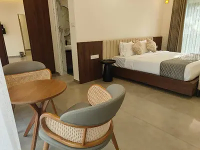 a bedroom with a bed and a table and chairs at Half Moon Resort Vythiri by Z Vacations in Vayittiri