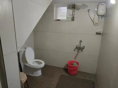 a small bathroom with a toilet and a red bucket at Deshadan's Kesarvilla in Palakkad
