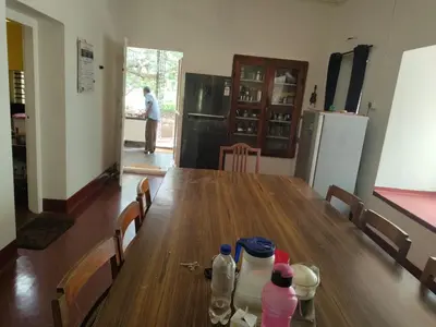 a long wooden table with chairs and a refrigerator at Deshadan's Kesarvilla in Palakkad