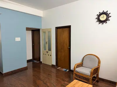 a room with a chair and a clock on the wall at Anand's Elegant 2BHK Apartment - AC in Mysore