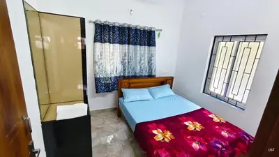 a small bedroom with a bed and two windows at Happy Homes in Palakkad