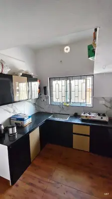 a kitchen with a black counter and two windows at Happy Homes in Palakkad