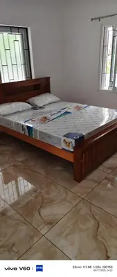 a bed sitting in a room with two windows at Happy Homes in Palakkad