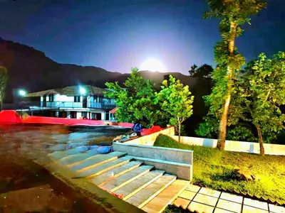 a bench in front of a building at night at Hermitage in Kurchi