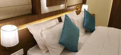 a bed with blue and white pillows in a room at Radha Madhavam Apartment's in Guruvāyūr