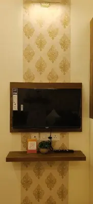 a flat screen tv hanging on a wall at Radha Madhavam Apartment's in Guruvāyūr