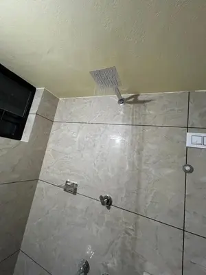 a shower in a bathroom with a tile floor at Bluebell Homes A - 3 BHK Near to Calicut in Beypore