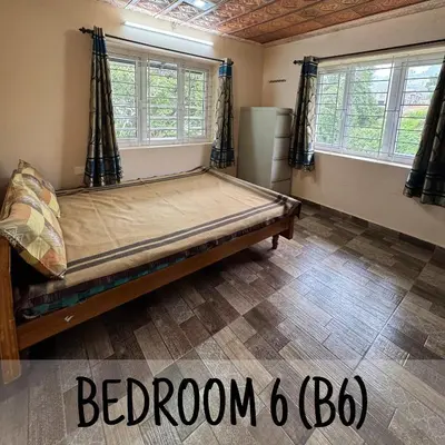 a bedroom with a bed in a room with windows at Ambassador Inn in Kodaikānāl