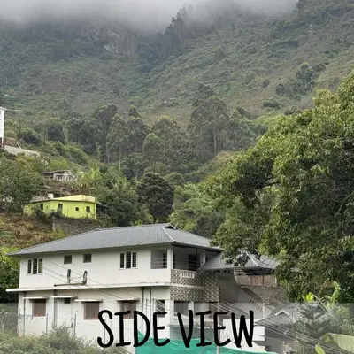 a white house in front of a mountain at Ambassador Inn in Kodaikānāl