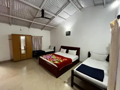 a bedroom with two beds and a chair in it at The Big Cat's Den - Maravakandy Resort, Masinagudi in Masinagudi