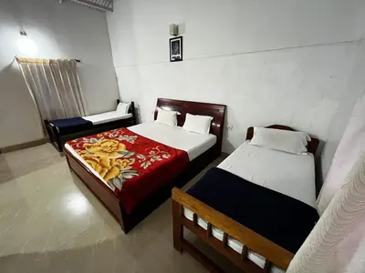 a bedroom with two beds and a chair in it at The Big Cat's Den - Maravakandy Resort, Masinagudi in Masinagudi