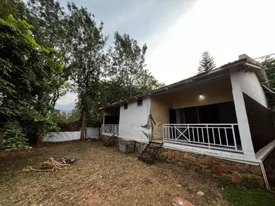 a white house with a porch and a yard at The Big Cat's Den - Maravakandy Resort, Masinagudi in Masinagudi