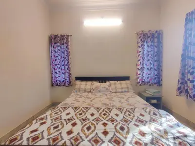 a bedroom with a bed and two windows at Spacious #3BHK Home Stay in Central Mysore in Mysore