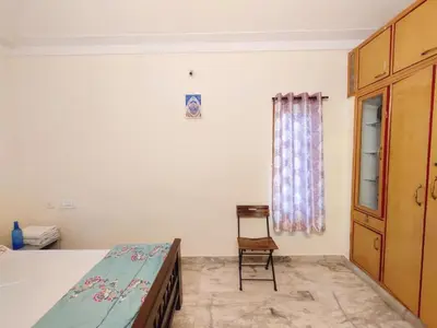a bedroom with a bed and a chair and a window at Spacious #1BHK Home Stay in Central #Mysore in Mysore