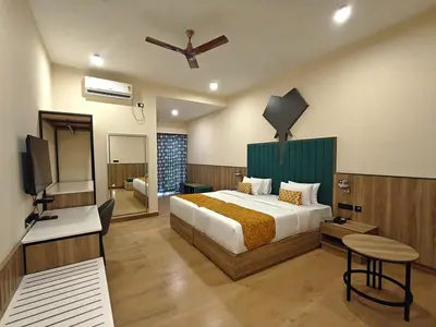 a bedroom with a bed and a television in a room at Tuskers Hill Banquets by Poppys - Anaikatti in Palakkad