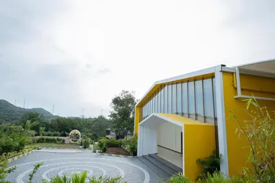 a yellow and white building with a garden at Tuskers Hill Banquets by Poppys - Anaikatti in Palakkad