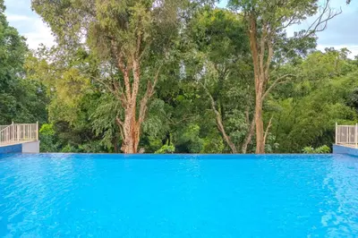 a pool of blue water with trees in the background at Tuskers Hill Banquets by Poppys - Anaikatti in Palakkad