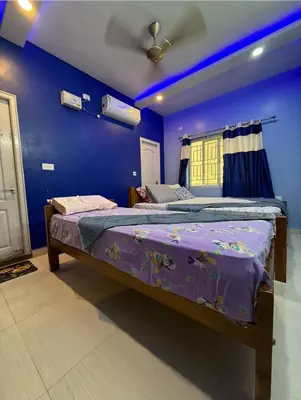 a bedroom with two beds and a blue wall at Spacious 3BHK Mountain View -walk to palani temple in Palani