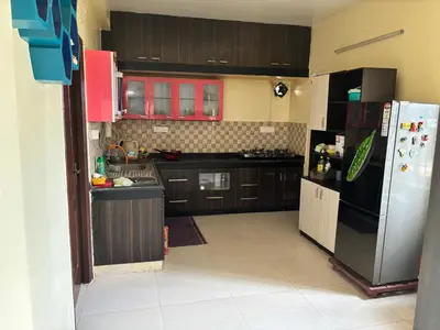 a kitchen with brown cabinets and a refrigerator at Spacious 3BHK Mountain View -walk to palani temple in Palani