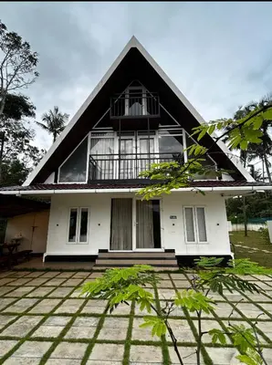 a white house with a black roof at Nirvana-Vadanappally Beach Villa in Irimbranallūr