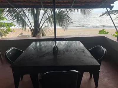a table with chairs and a view of the beach at Rocks beach house in Kannur