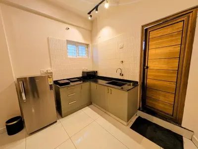 a kitchen with a sink and a refrigerator at Sihi Homes in Mysore