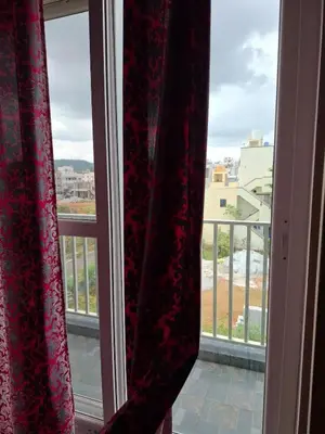 a window with curtains and a view of a city at Belaku in Chāmundi