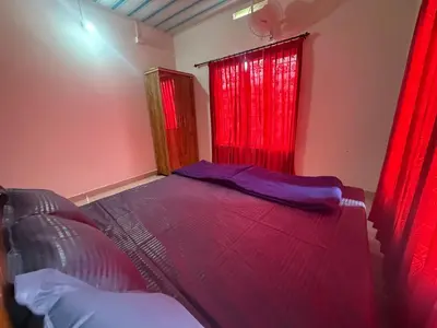 a bedroom with a large bed with red curtains at Cosy Kalpetta Villa in Kalpetta