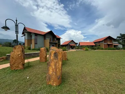 a group of rocks in the grass in front of a house at Birdwing - Experiential Farmstay Resort by GoodEarth