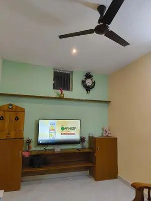 a living room with a tv and a ceiling fan at Coorg Refresh Homestay in Kushālnagar