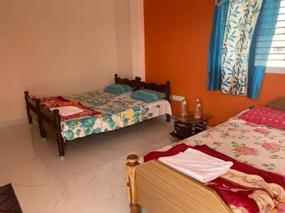 a room with two beds and two chairs in it at Abhi home stay in Mysore