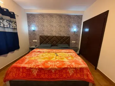 a bedroom with a large bed with an orange blanket at green mountain homestay in Ooty
