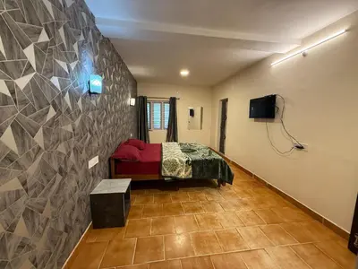 a bedroom with a bed and a tv on a wall at green mountain homestay in Ooty