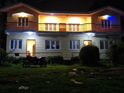 a house with a motorcycle parked in front of it at night at green mountain homestay in Ooty