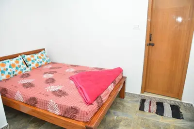 a bedroom with a bed with a pink blanket on it at Murugan Homestays in Vālpārai