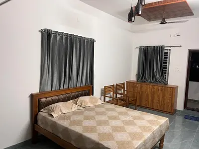 a bedroom with a bed and two windows with curtains at The coconest Kinathukadavu, Coimbatore in Kinattukkadavu