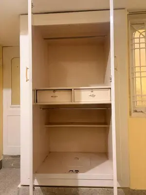 an empty closet with white shelves in a room at The Green residence in Mysore