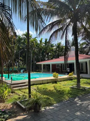 a resort with a swimming pool and palm trees at SARA fARM STAY