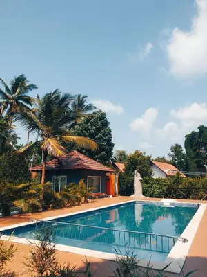 a swimming pool in front of a house at DJ River Meadows Resort in Wayanad