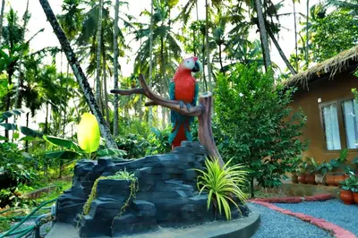 a statue of a red parrot sitting on a branch at DJ River Meadows Resort in Wayanad