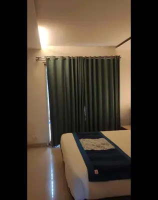 a bedroom with a bed and a window with curtains at Mysore Central 3bhk serviced apartment in Mysore