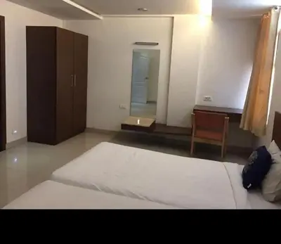 a bedroom with a large bed and a chair at Mysore Central 3bhk serviced apartment in Mysore